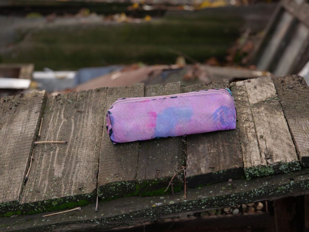 A pink school pencil case lies on a wooden table